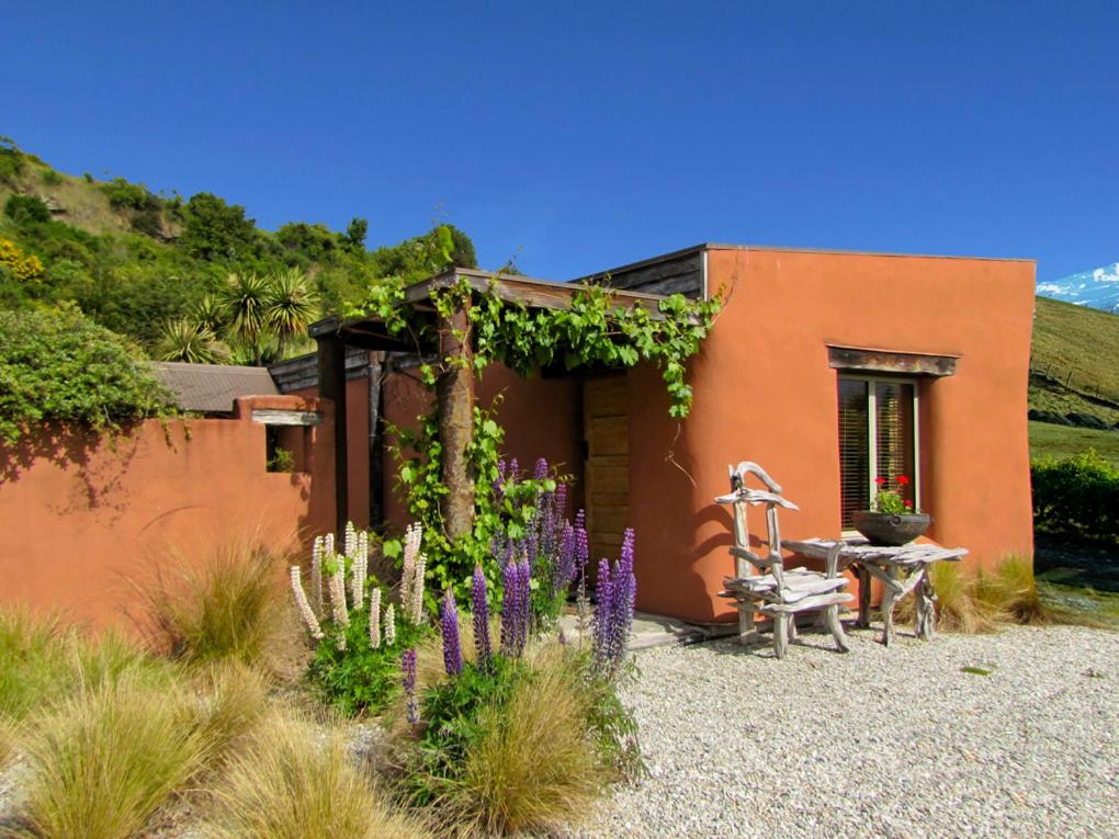 a house with a table and a chair and flowers at Tussock Cottage in Queenstown