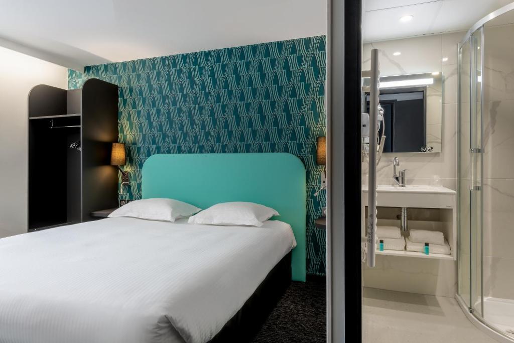 a bedroom with a large bed and a bathroom at Zenith Hotel Caen in Caen