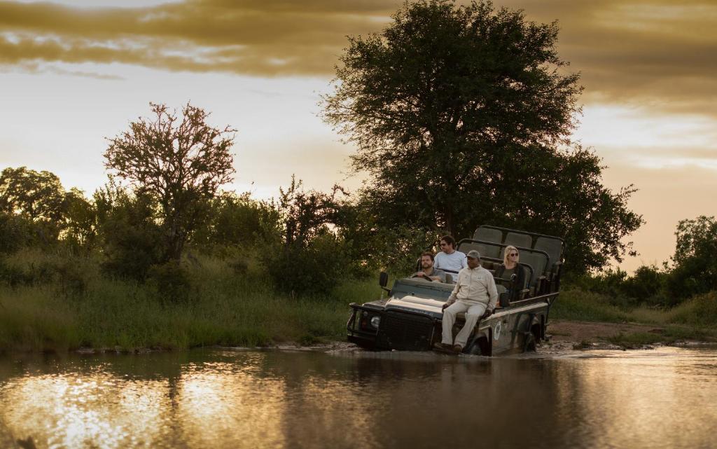 a group of people riding in a truck in a river at Kambaku River Sands in Timbavati Game Reserve