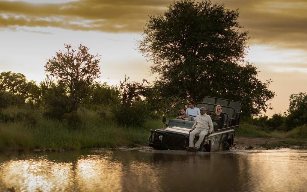 un grupo de personas montando en un camión en un río en Kambaku River Sands, en Reserva Timbavati