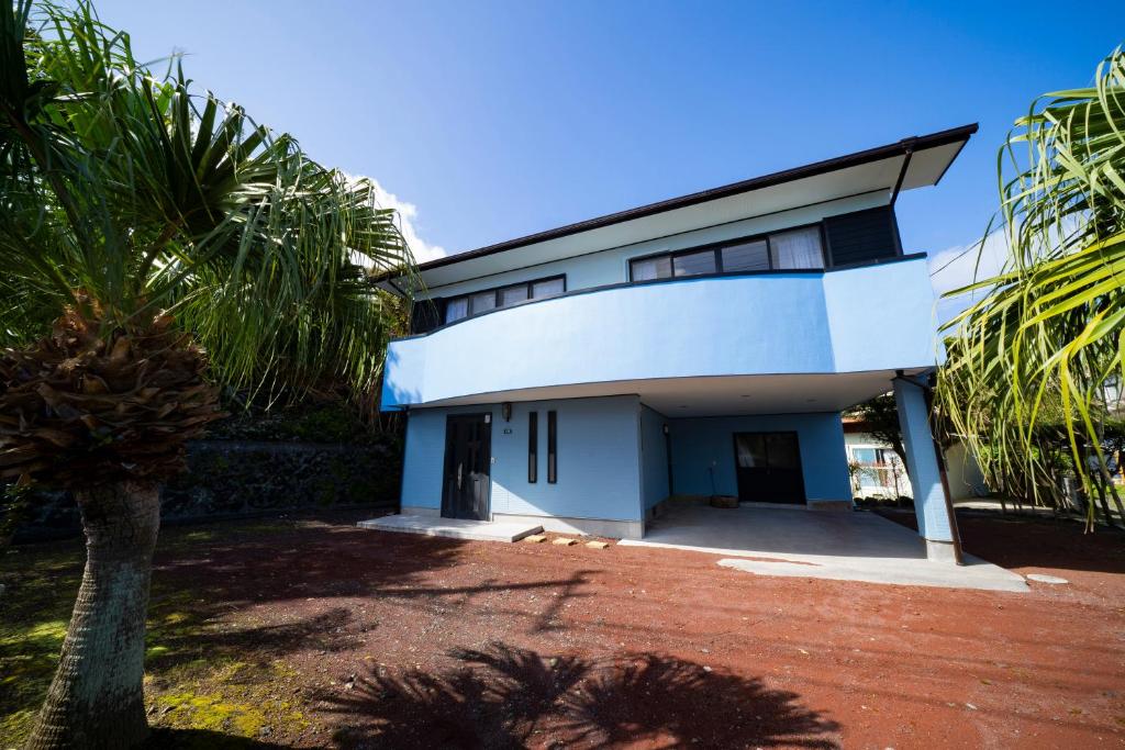 a white house with a palm tree in front of it at Hachijyo-island Blue Eight -八丈島ブルーエイト- in Mitsune