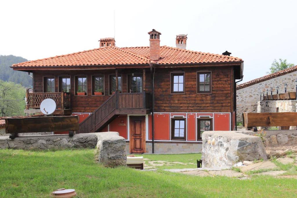 a large red house with a deck on a field at Red House in Koprivshtitsa