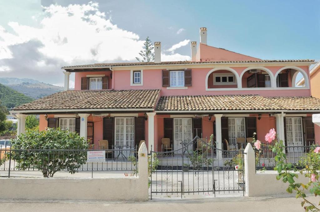 卡西奧皮的住宿－卡拉米奧納斯公寓，粉红色的房子,前面有栅栏