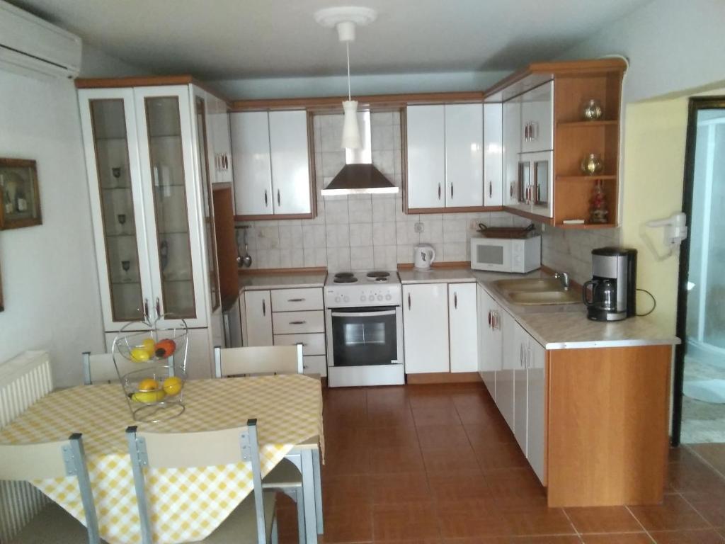 a kitchen with white cabinets and a table with a tableablish at VILLA KONSTANTINA in Nea Skioni