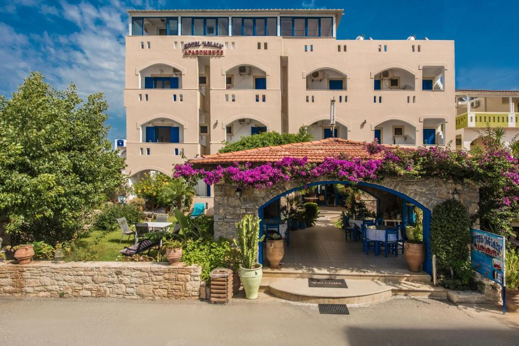 卡拉馬基的住宿－Hotel Aglaia，一座白色的大建筑,前面有紫色的花朵