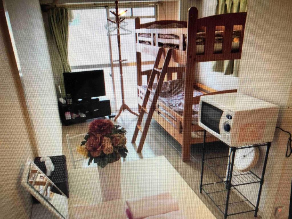 Kleines Zimmer mit einem Etagenbett und einer Mikrowelle. in der Unterkunft San Grace West Park I / Vacation STAY 4504 in Fukuoka