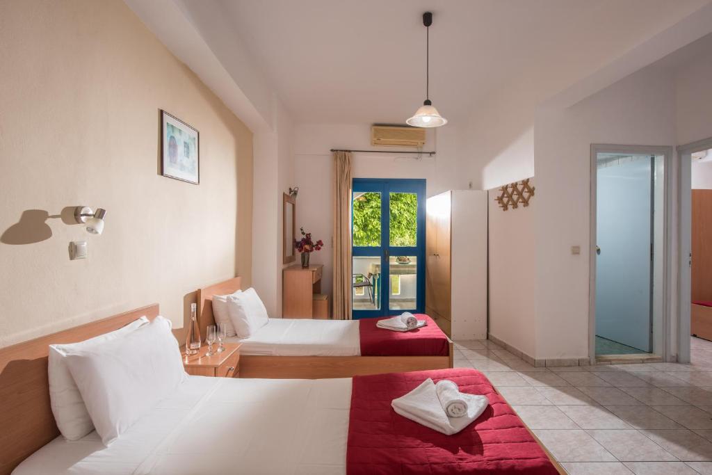 a hotel room with two beds and a window at Hotel Aglaia in Kalamaki