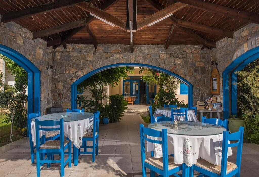 a patio with blue tables and chairs and a stone wall at Hotel Aglaia in Kalamaki
