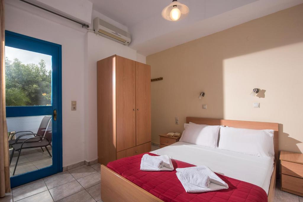 a bedroom with a bed and a chair and a window at Hotel Aglaia in Kalamaki