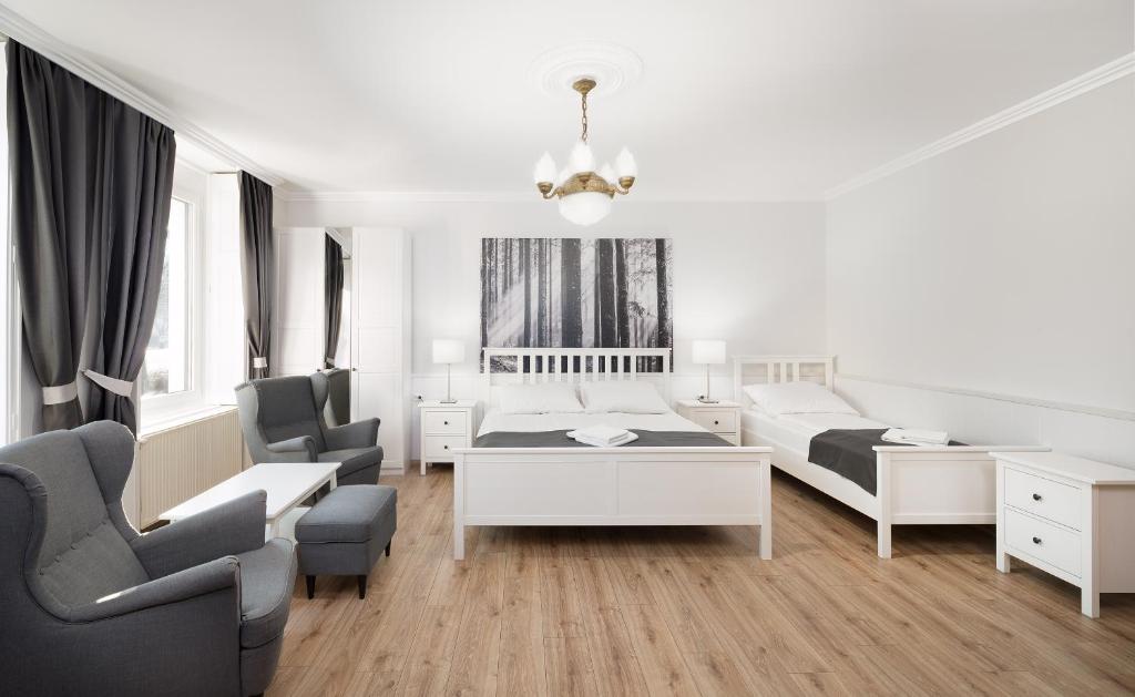 a white room with a bed and two chairs at Provence Apartmanok in Visegrád