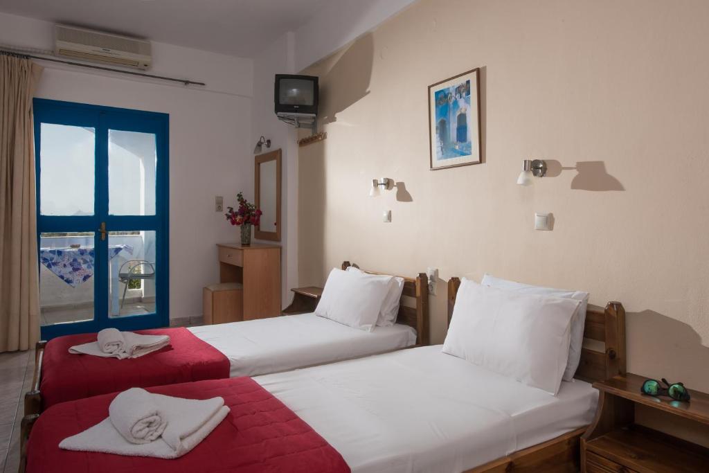 two beds in a room with a window at Hotel Aglaia in Kalamaki