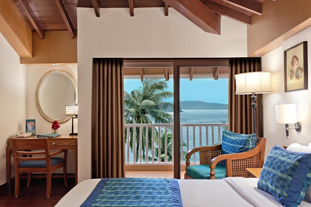 a bedroom with a bed and a desk and a balcony at Welcomhotel by ITC Hotels, Bay Island, Port Blair in Port Blair