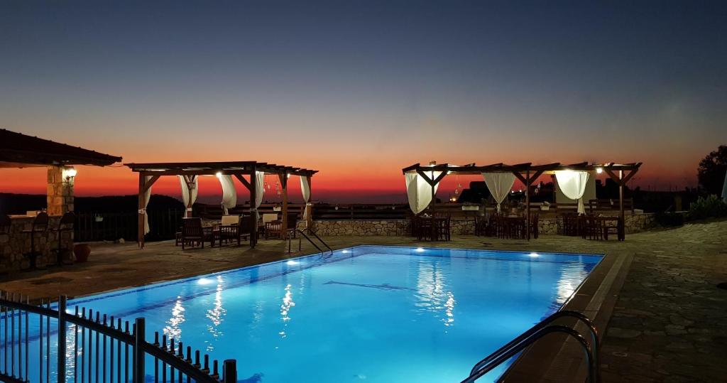 a swimming pool with a sunset in the background at Ataviros Hotel in Émbonas