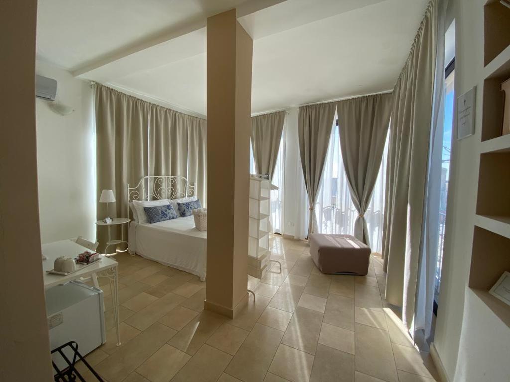 a bedroom with a white bed and large windows at Regina Margherita B&B in Marzamemi