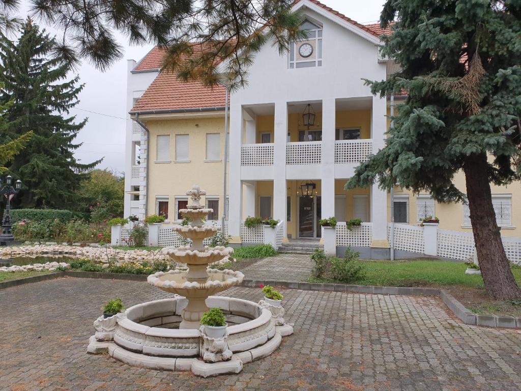 una fuente frente a una casa grande en Kiskunlacháza 6, en Kiskunlacháza