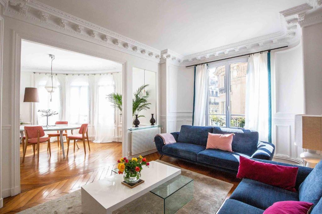 un salon avec un canapé bleu et une table dans l'établissement Veeve - Pastel Pinks in Paris, à Paris