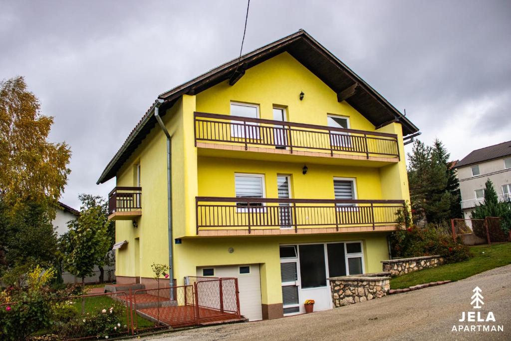a yellow house with a balcony on top of it at Apartman Jela in Kupres