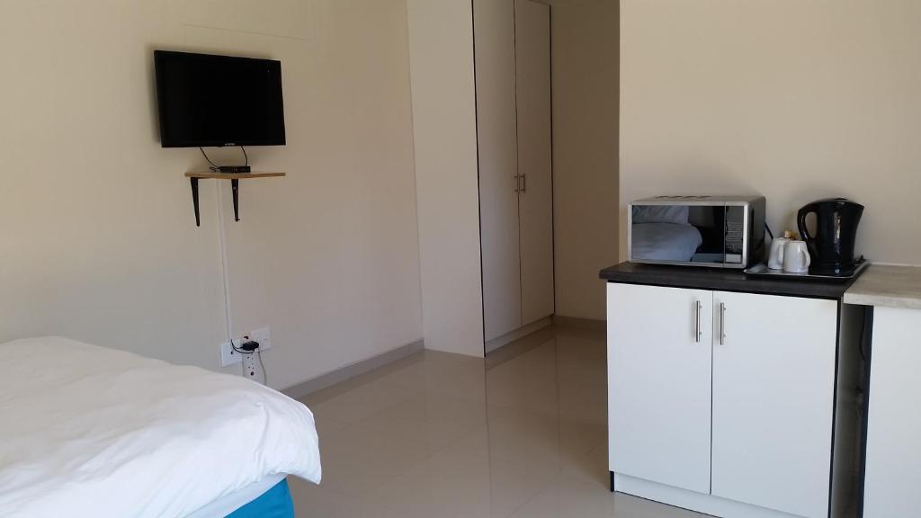 a bedroom with a bed and a tv on a counter at Dolphin Guest House in Walvis Bay