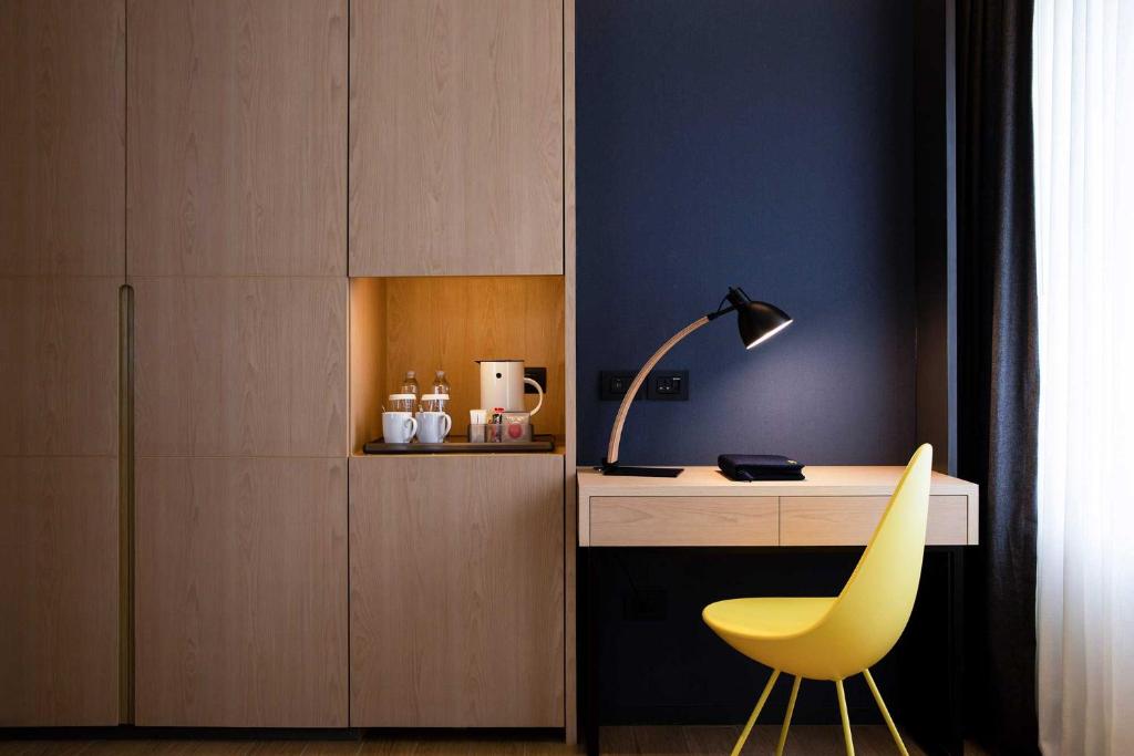 A built-in work desk with a yellow chair, task lamp and beverage station.