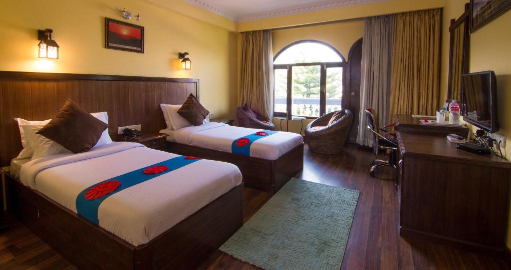 a hotel room with two beds and a desk at Hotel The Kantipur in Pokhara