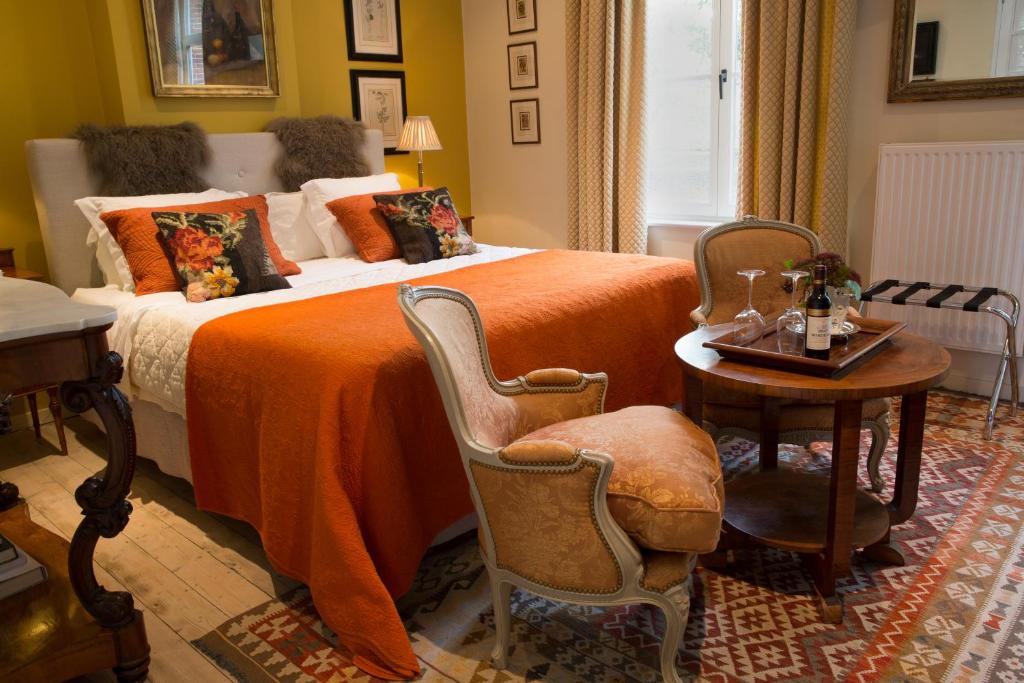 TWO ROOMS IN BRUGES في بروج: غرفة نوم بسرير وبطانية برتقالية وطاولة