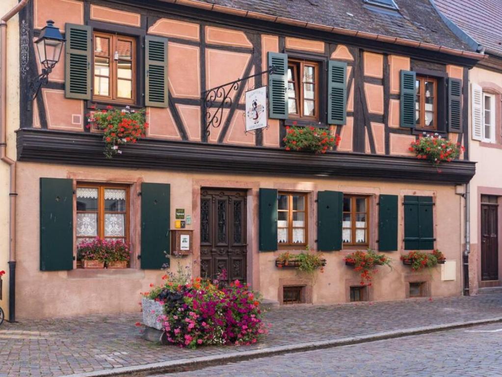 un bâtiment avec des fleurs en face, dans une rue dans l'établissement Maison de 2 chambres avec wifi a Kientzheim, à Kientzheim