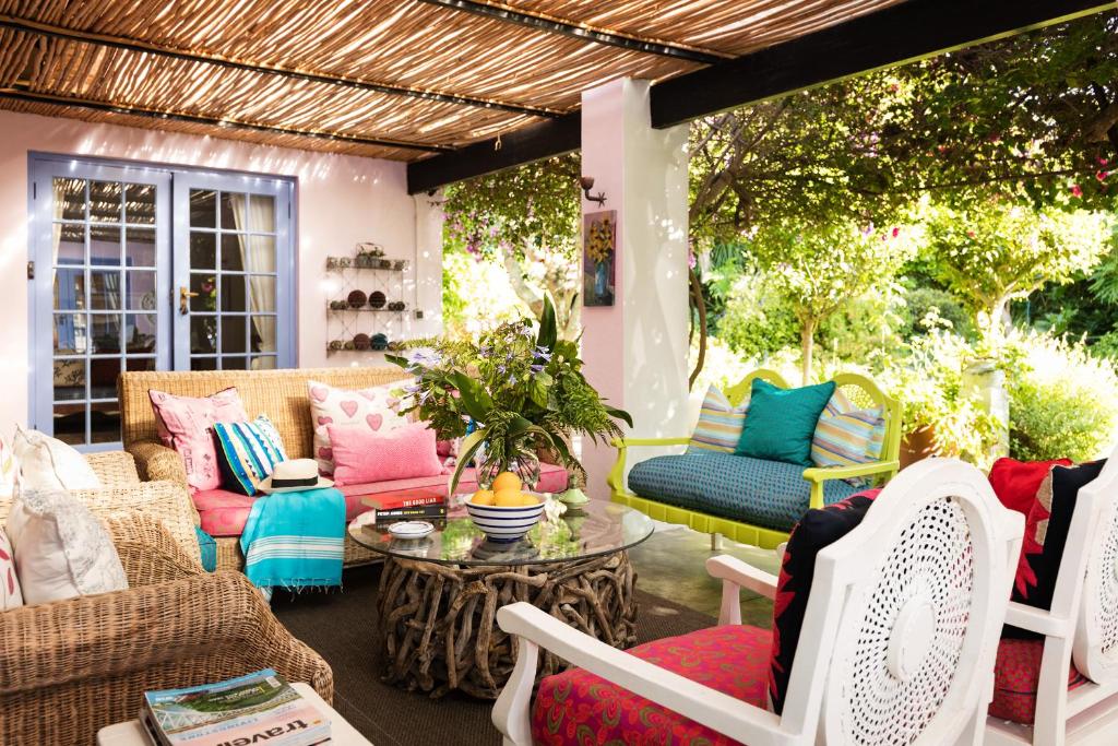 a patio with colorful chairs and a table at Cornerway House in Plettenberg Bay