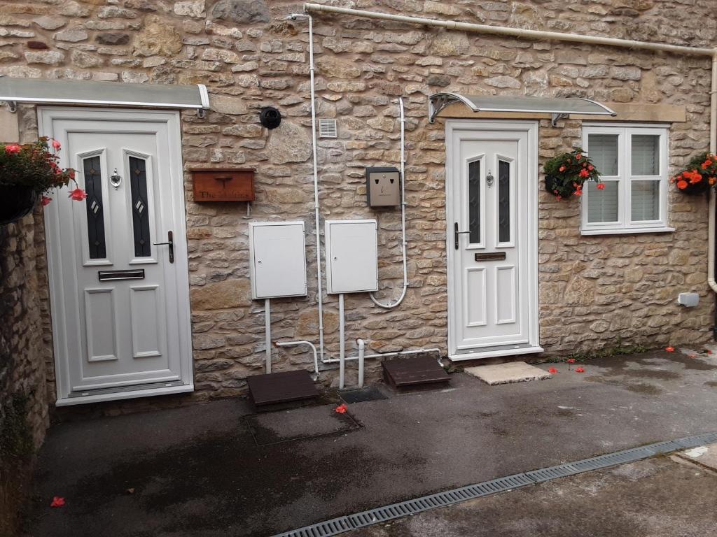 um edifício de pedra com duas portas brancas em The Maltings - Apartments 1 em Shepton Mallet