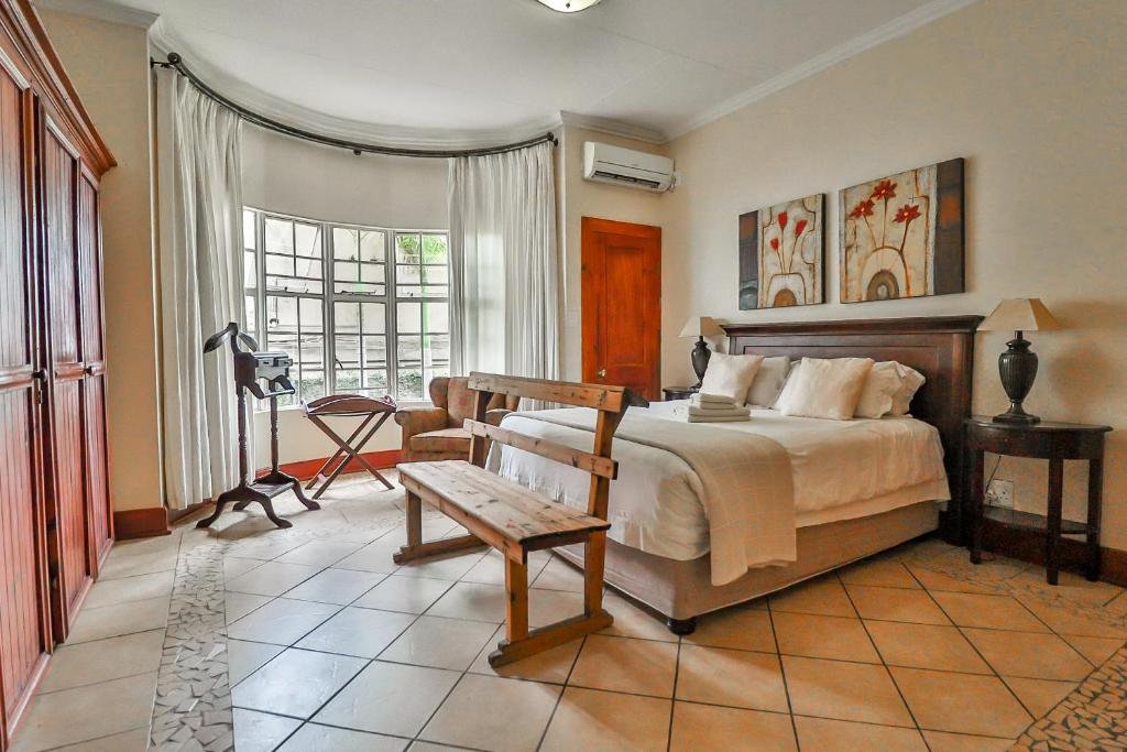a bedroom with a bed with a bench in it at Croc River Lodge in Komatipoort