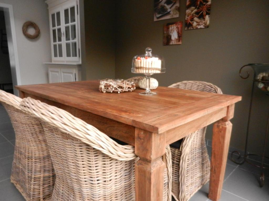 una mesa de comedor con sillas de mimbre alrededor en Holiday Home Juliette, en Poperinge