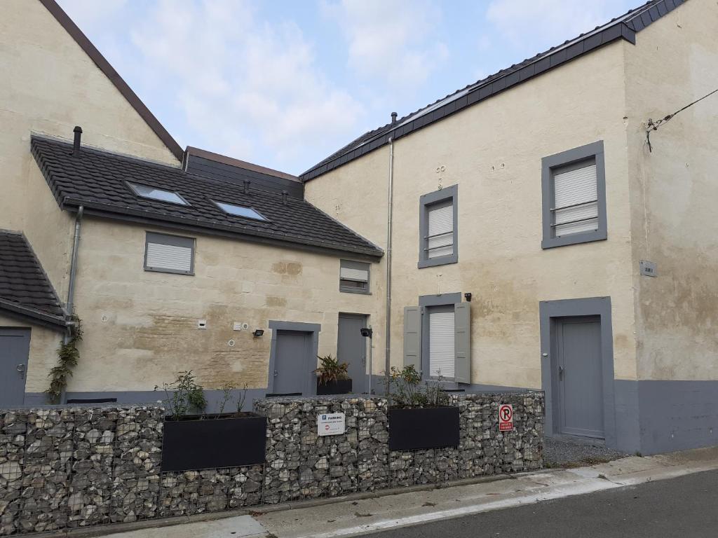 una casa con una pared de piedra de retención delante de ella en Les gîtes du Broukay - Hirondelle, en Bassenge