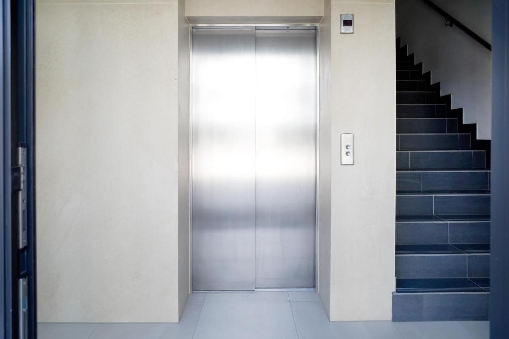 a metal elevator door in a building with stairs at Platinium Rewal Aparthotel 19 in Rewal