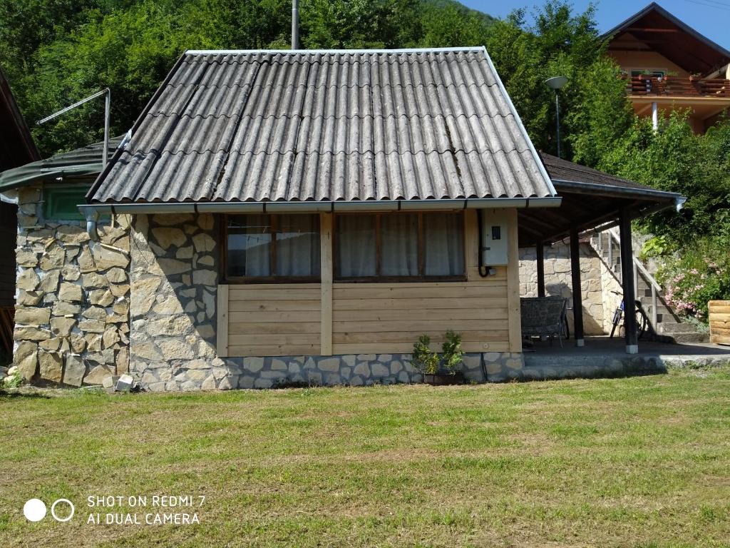 a small house with a roof on a yard at Perucac Jezero in Perućac
