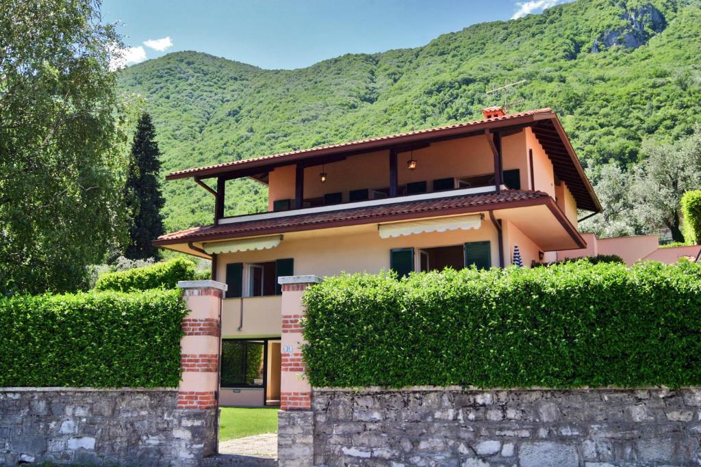 a house behind a hedge with a mountain in the background at La Spiaggia in Oliveto Lario