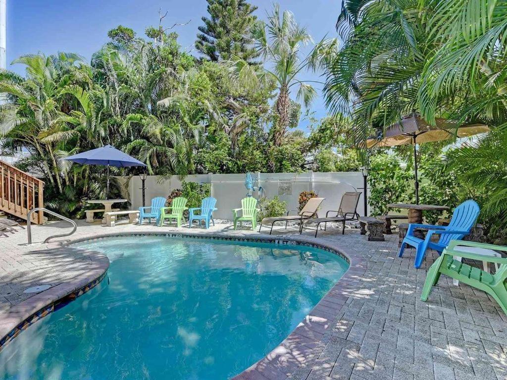 ブレイデントン・ビーチにあるIdeal beach hideaway pool condo located between the island marina and beachの青と緑の椅子とテーブル付きのスイミングプール