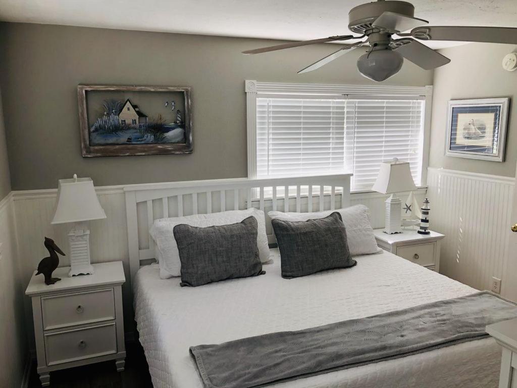 a bedroom with a white bed with a ceiling fan at Amazing beach getaway pool condo by the beach in Bradenton Beach