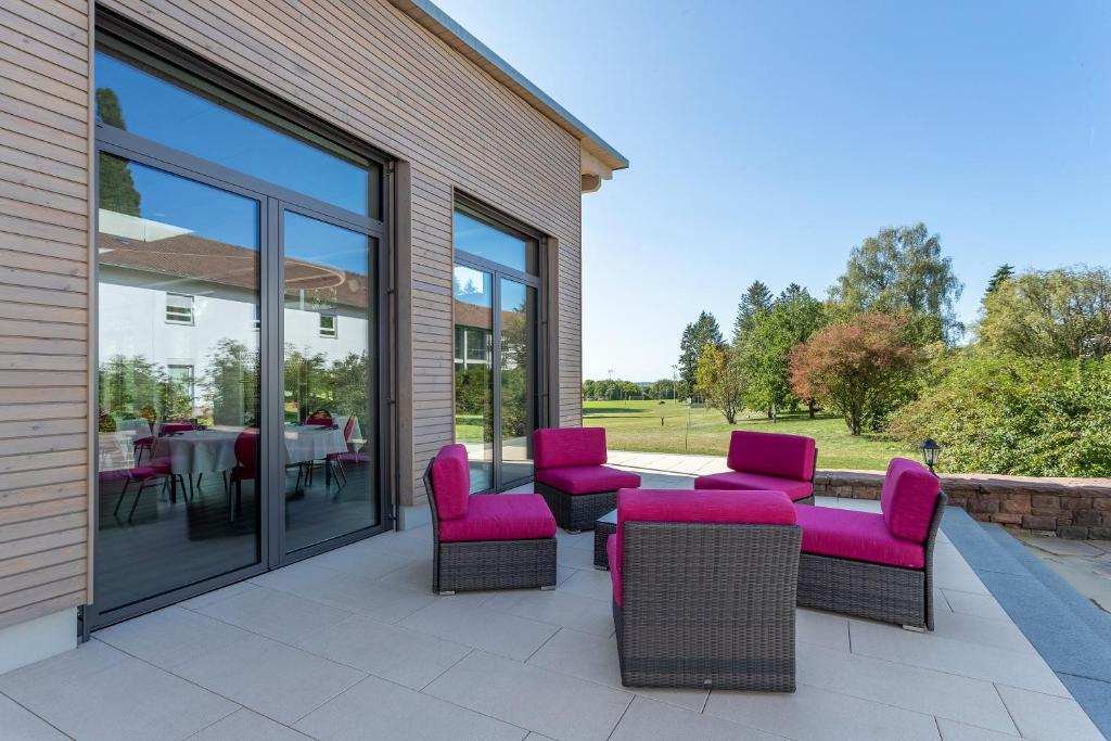 a patio with purple chairs and tables and windows at Sporthotel Grünberg in Grünberg
