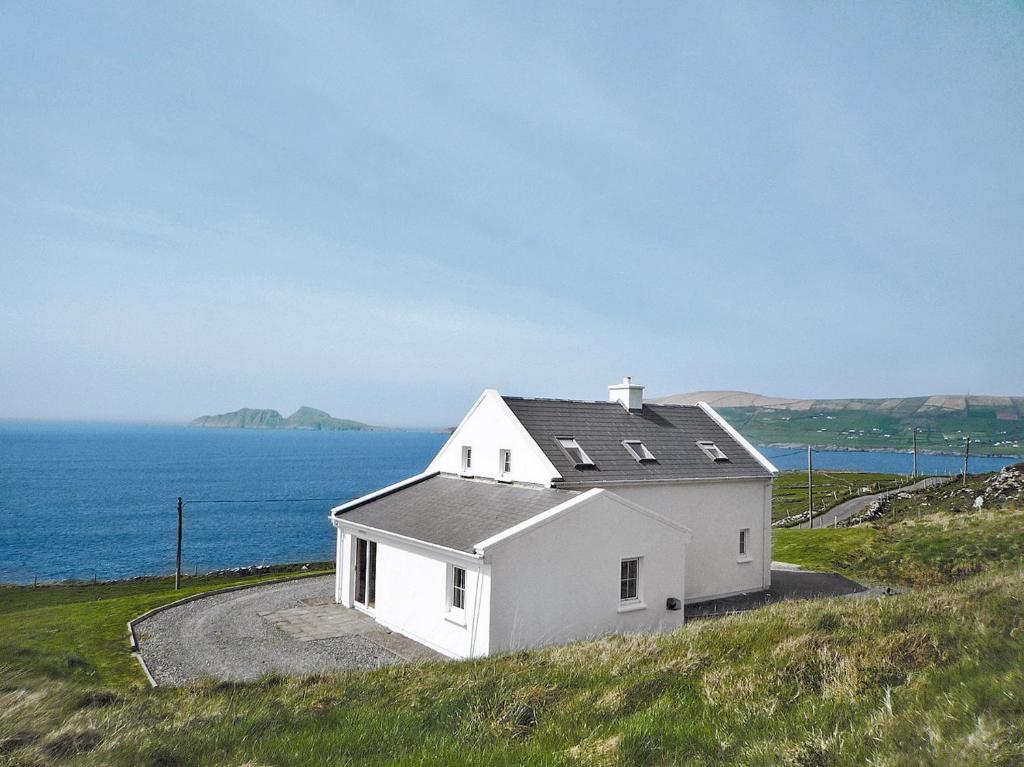 una casa blanca en una colina junto al océano en Allaghee Mor St Finians Bay en Ballinskelligs