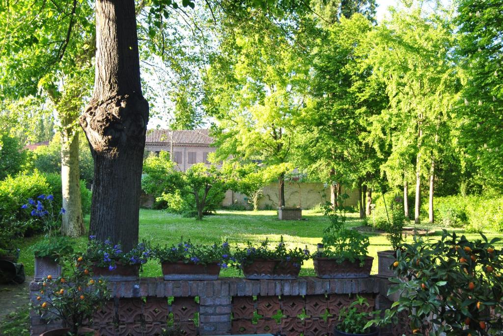 a garden with flowers and a tree and a stone fence at Vicolo Parchetto 9 in Ferrara