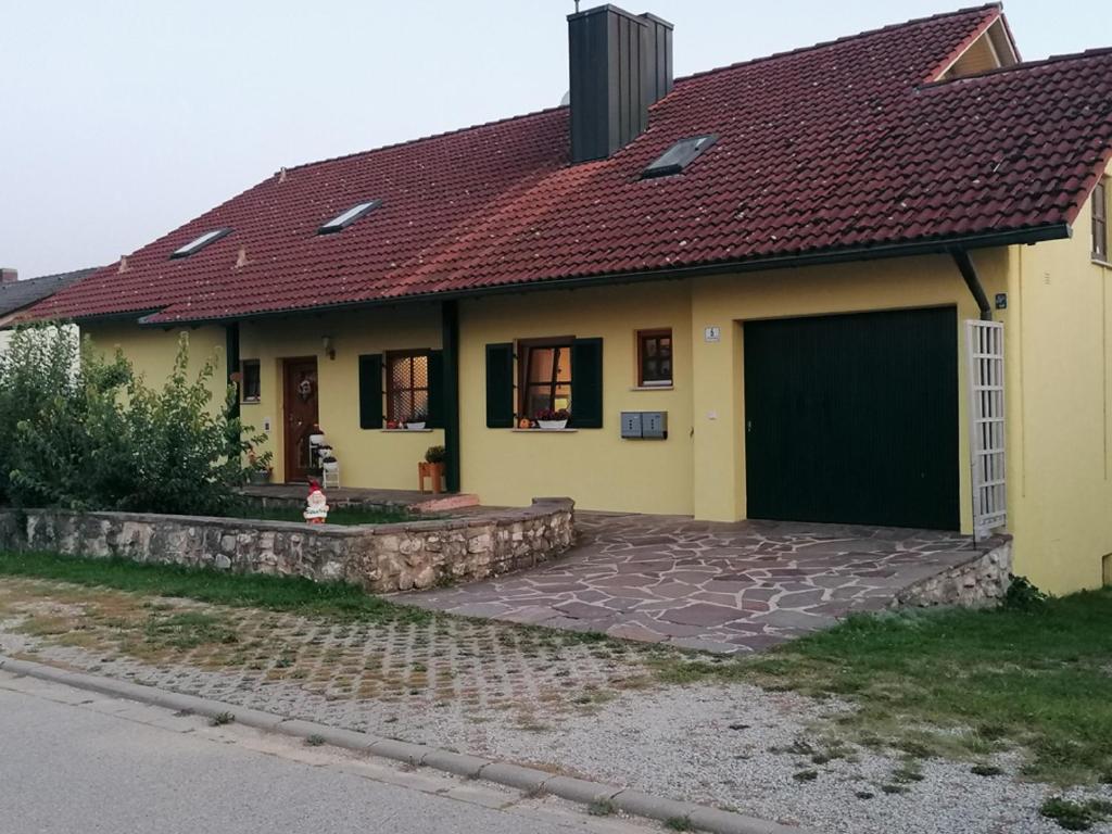 a yellow house with a red roof and a driveway at Komfort Feriendomizil JAKOBI in Dietfurt