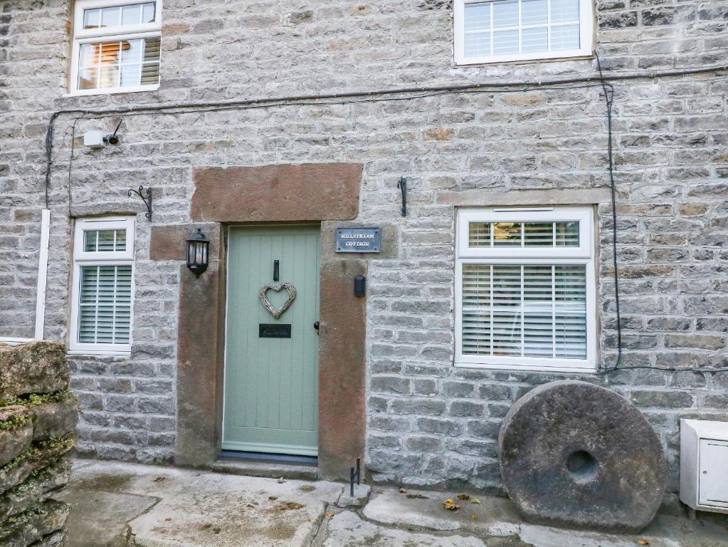 un edificio de ladrillo con una puerta con un signo cardíaco. en Millstream Cottage, en Castleton