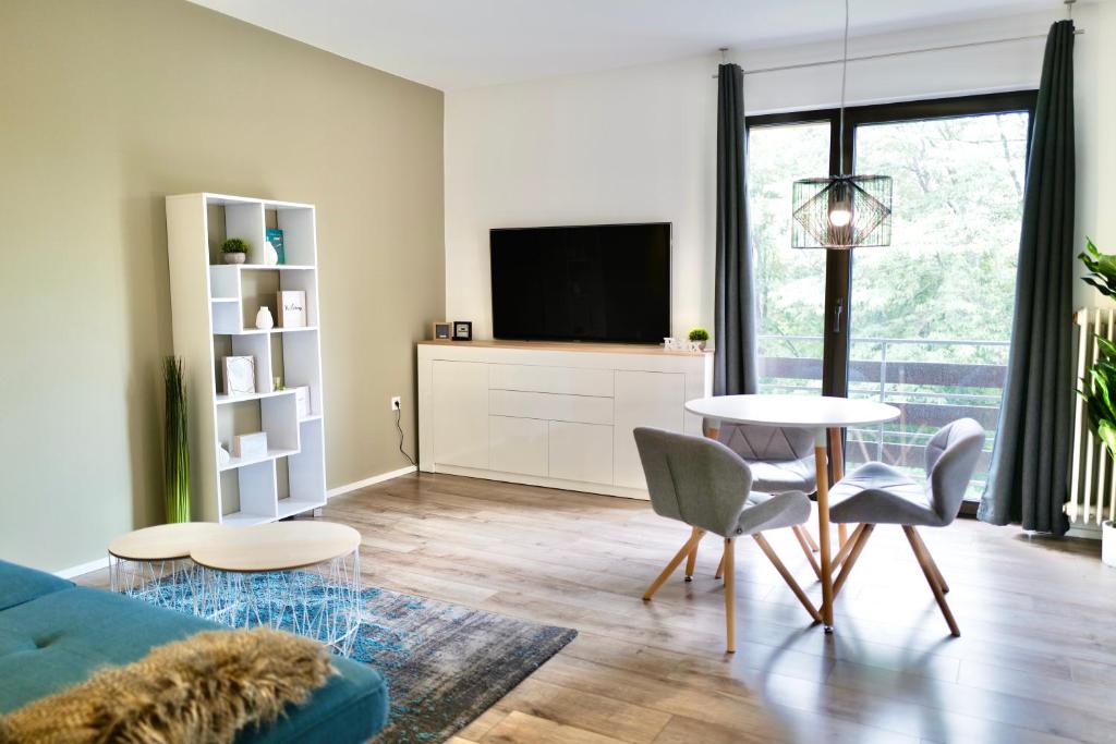 een woonkamer met een bank, een tafel en een tv bij Seven in Koblenz