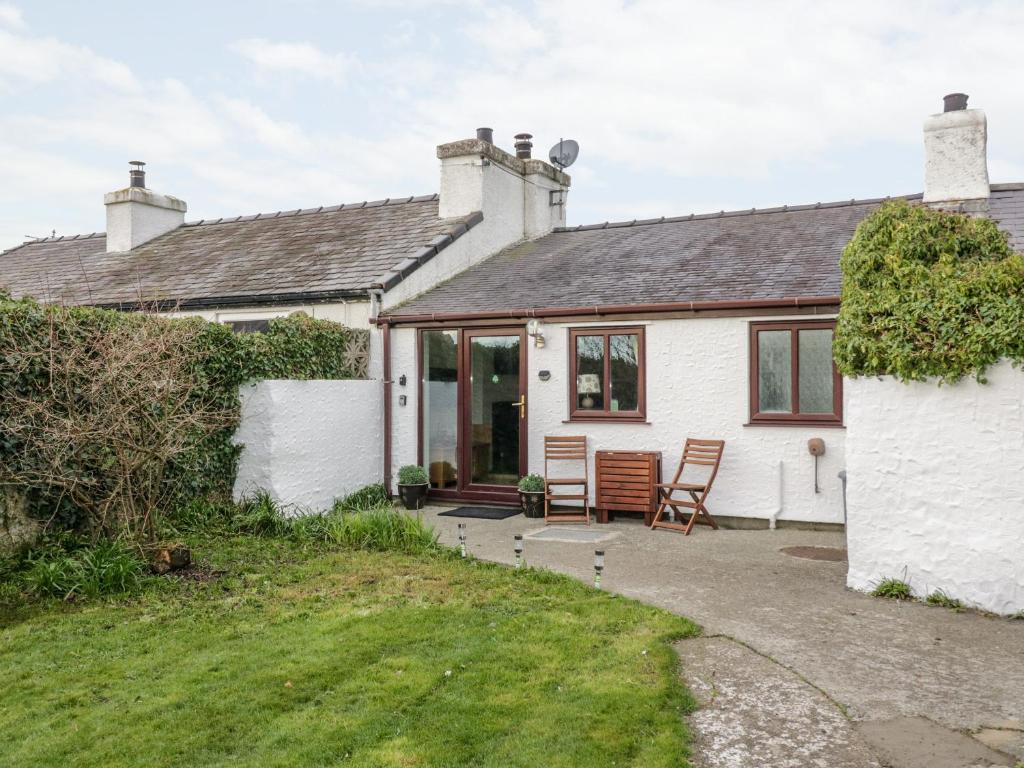 a white house with a patio in front of it at Bwthyn in Moelfre