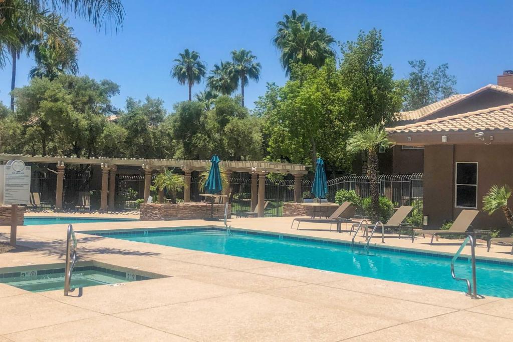 a pool with chairs and umbrellas in a resort at Scottsdale Condo with Pool Walk to Kierland Resort in Scottsdale