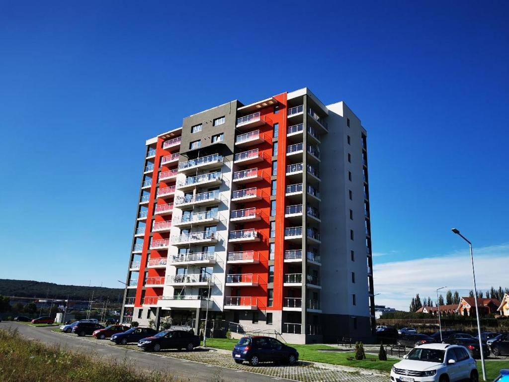 un edificio de apartamentos alto con coches estacionados en un estacionamiento en Studio Green, en Târgu Mureș