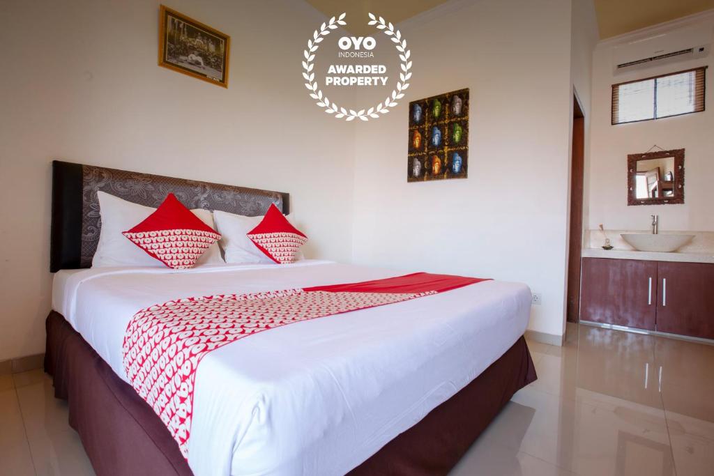a bedroom with a large bed and a sink at OYO 401 The Frog Homestay Sanur in Sanur