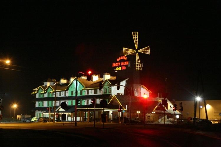 ein großes Gebäude mit einem Kreuz darüber in der Nacht in der Unterkunft Hotel Złoty Młyn Majków in Piotrków Trybunalski