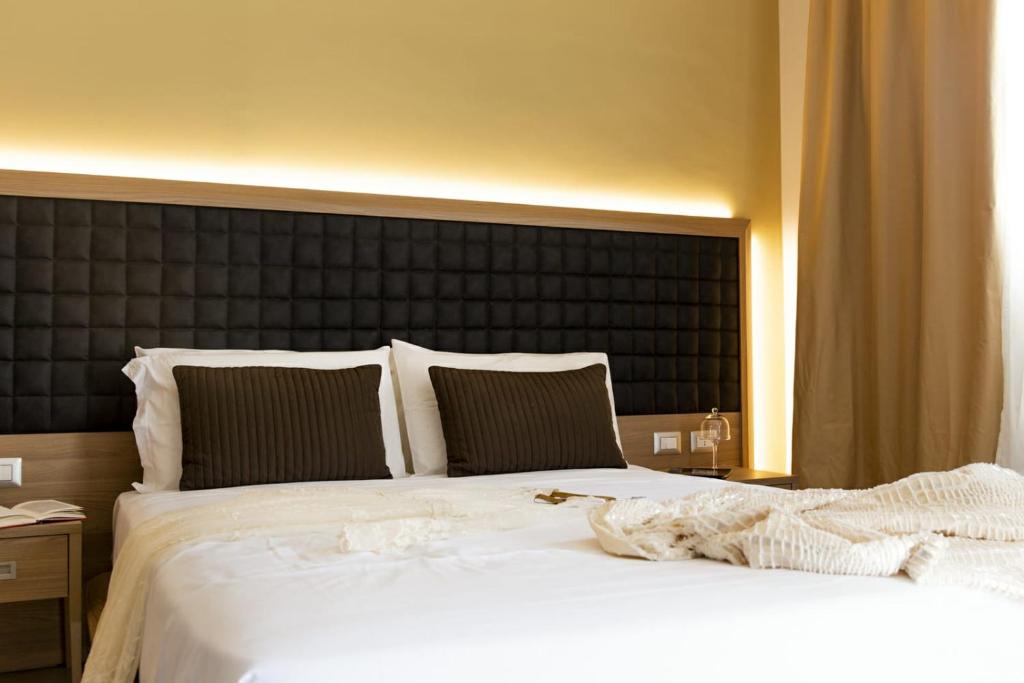 um quarto com uma grande cama branca e uma cabeceira preta em Hotel San Vincenzo Resort em Policoro