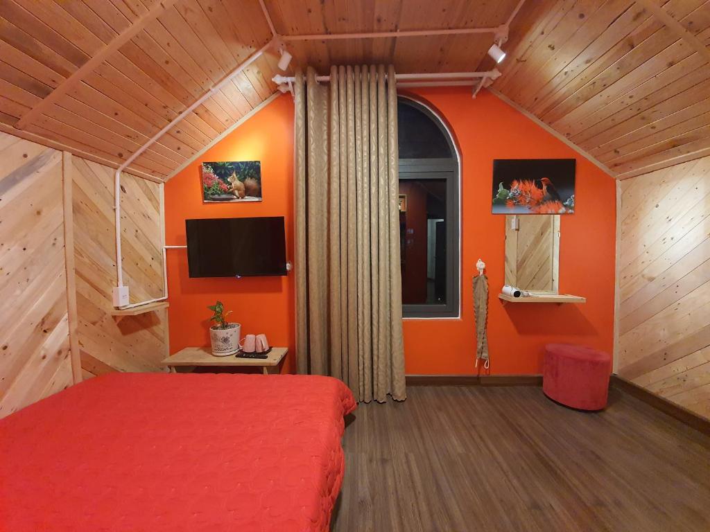 Schlafzimmer mit orangefarbenen Wänden, einem Bett und einem Fenster in der Unterkunft Lightning House 2 in Da Lat