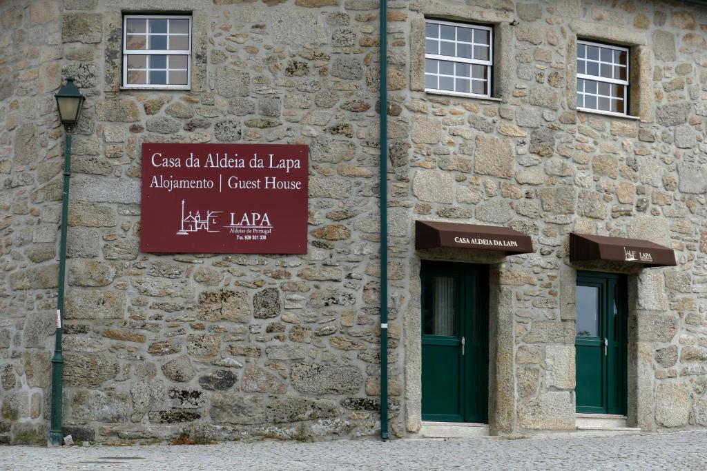 a stone building with two windows and a sign on it at Casa Aldeia da Lapa in Sernancelhe